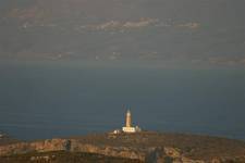 the lighthouse at the northern end of the island at cape spathi with napoli and mainland greece in the background.