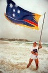George C Poulos gambolling in the surf at Bondi Beach with the official Bondi Beach Flag - his own design 