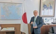 Ambassador of Japan to Greece Masuo Nishibayashi holding a copy of Lafcadio Hearn's Japanese Miscellany 