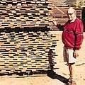 Brinos Notaras in front of a stack of blackbutt boards, drying. 